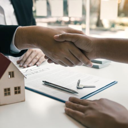 Home sales agents and buyers work on signing new homes and shaking hands.